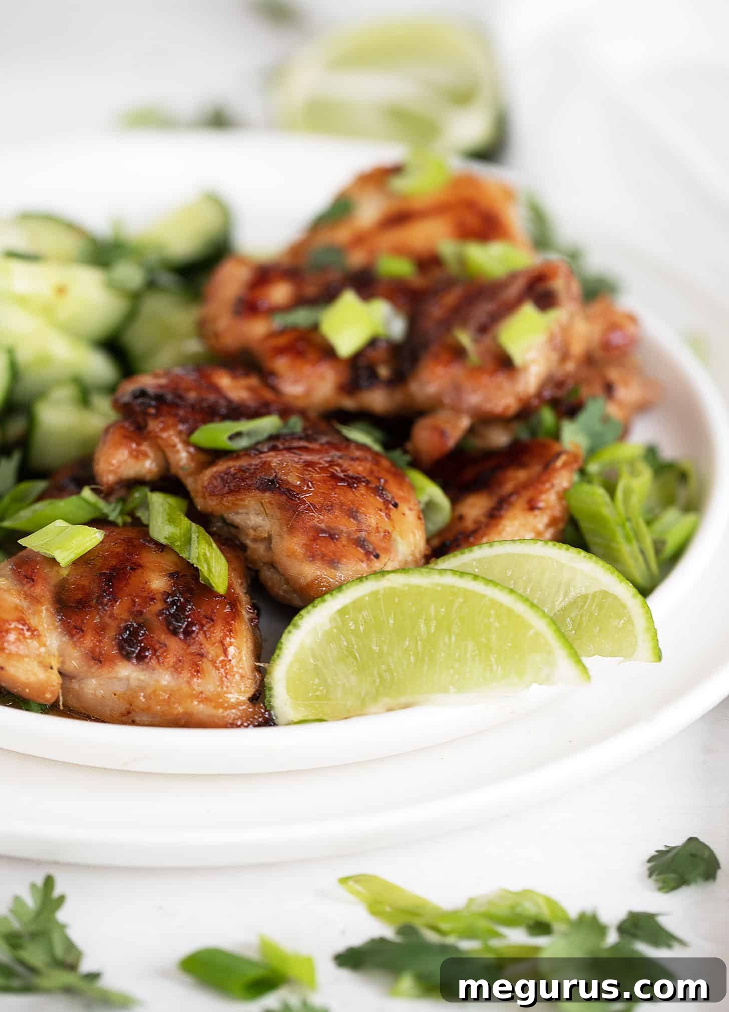 Two grilled lemongrass chicken thighs on a plate, garnished with fresh cilantro.