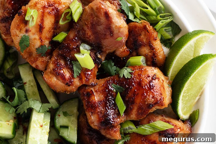 Grilled Lemongrass Chicken Thighs on a plate with fresh herbs and lime wedges.