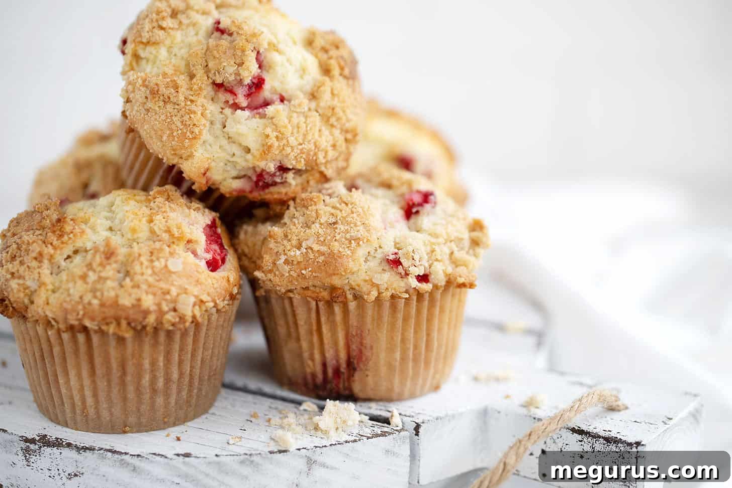Delicious strawberry rhubarb muffins arranged artfully on a wooden serving board, showcasing their golden-brown streusel topping and vibrant fruit.