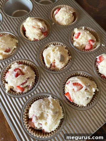 Muffin batter neatly scooped into paper-lined muffin cups, ready for topping and baking.