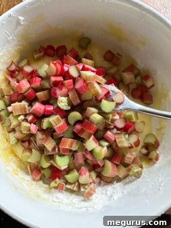 Finely diced rhubarb being added to the custard filling mixture in a bowl.