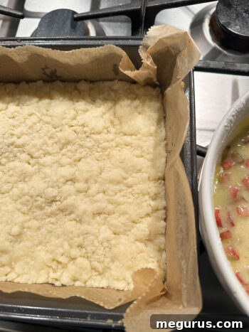 Pre-baked shortbread base in the pan, next to a bowl of ready custard rhubarb filling.