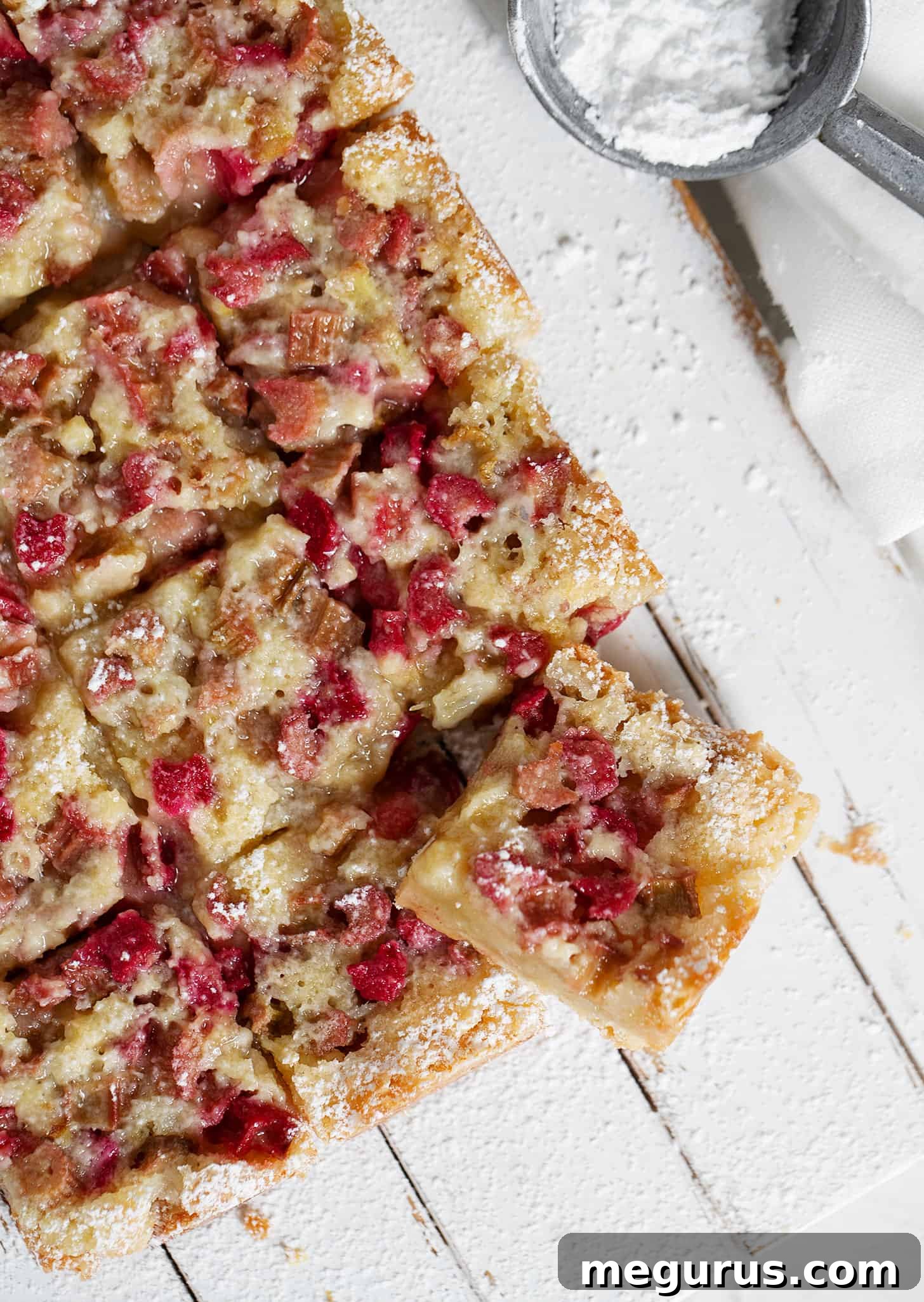 Close-up of old-fashioned rhubarb bars on a wooden serving board, showing the crisp shortbread and perfectly set custard.