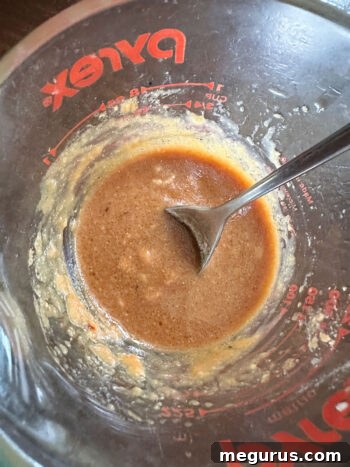Miso marinade ingredients being mixed in a measuring cup.