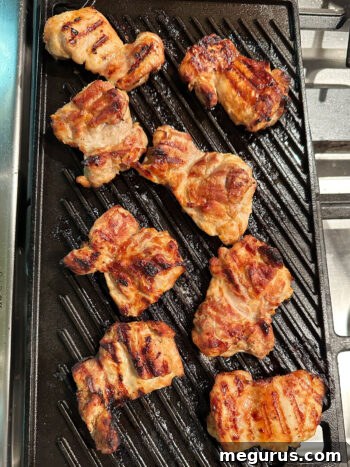 Grilled miso chicken thighs resting on a grill pan after cooking.