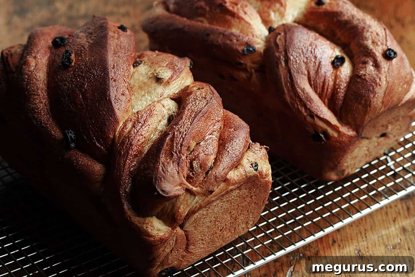 Beautifully twisted cinnamon raisin bread cooling on a wire rack, showcasing its intricate cinnamon swirls and golden-brown crust.