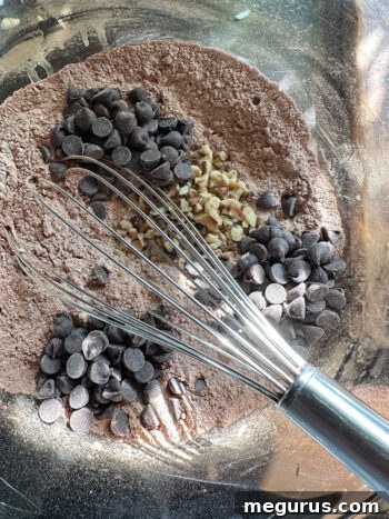 Adding chocolate chips and chopped walnuts to the dry ingredients mixture.