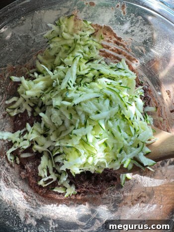 Folding shredded zucchini into the muffin batter.