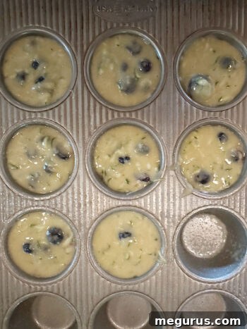 Muffin batter scooped into paper-lined muffin cups, ready for baking.