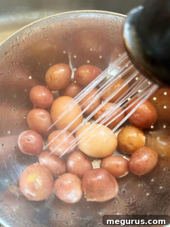 Rinsing cooked potatoes and eggs under cold water in a colander