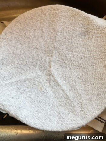 Steaming potatoes in a colander covered with a tea towel