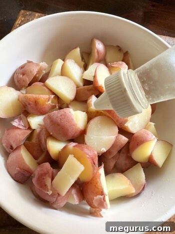 Drizzling white vinegar over warm, chopped potatoes
