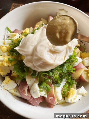 Adding mayonnaise and Dijon mustard to the potato salad ingredients