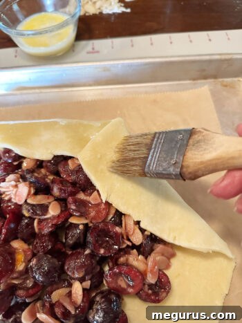 Brushing the folded edge of the galette pastry with an egg wash before baking