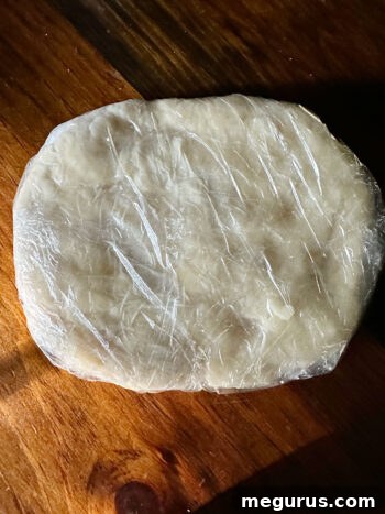 Dough tightly covered in plastic wrap, ready for refrigeration