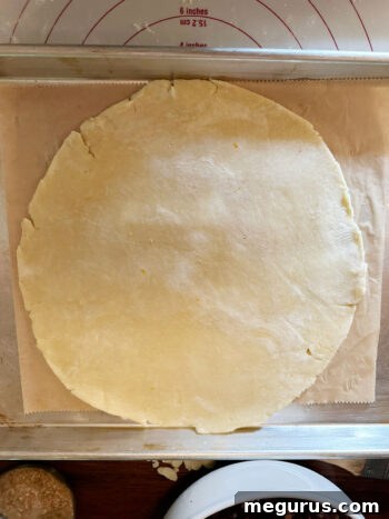 Rolled pastry round carefully transferred onto a parchment-lined baking sheet