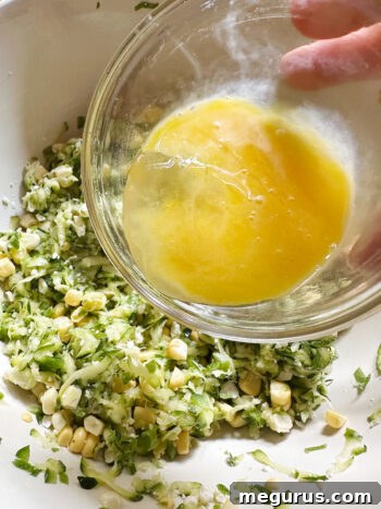 A lightly beaten egg being added to the vegetable mixture in a bowl.