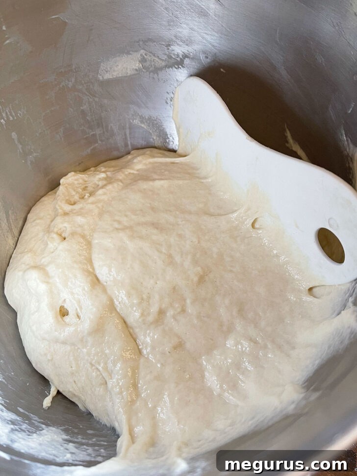 Scraping the sticky English Muffin Bread dough from the mixing bowl.