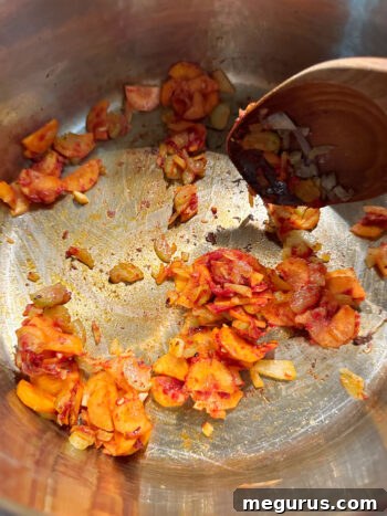 adding tomato paste to softened vegetables