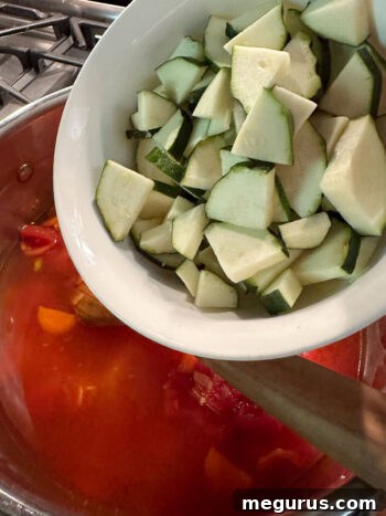 adding zucchini to soup