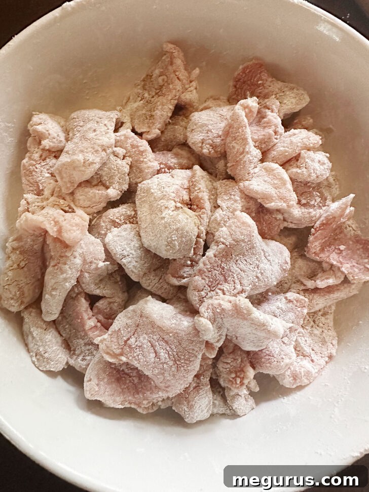 Marinated pork being coated evenly in cornstarch