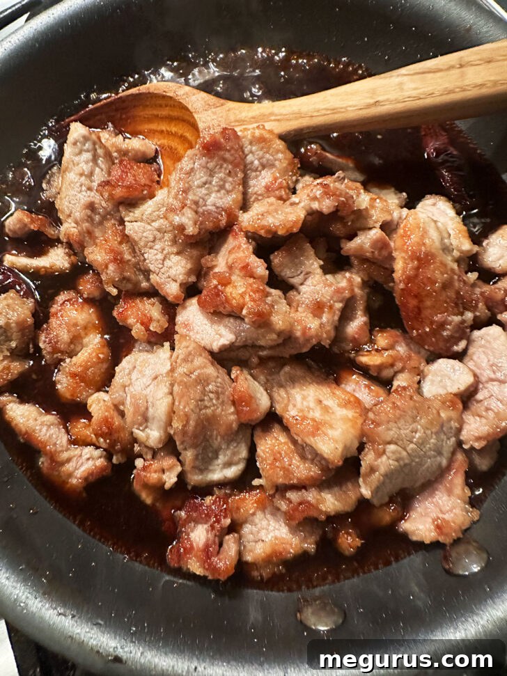 Returning browned pork to a skillet with the thickened Mongolian sauce