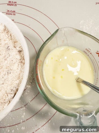 wet ingredients in measuring cup next to bowl with flour butter mixture