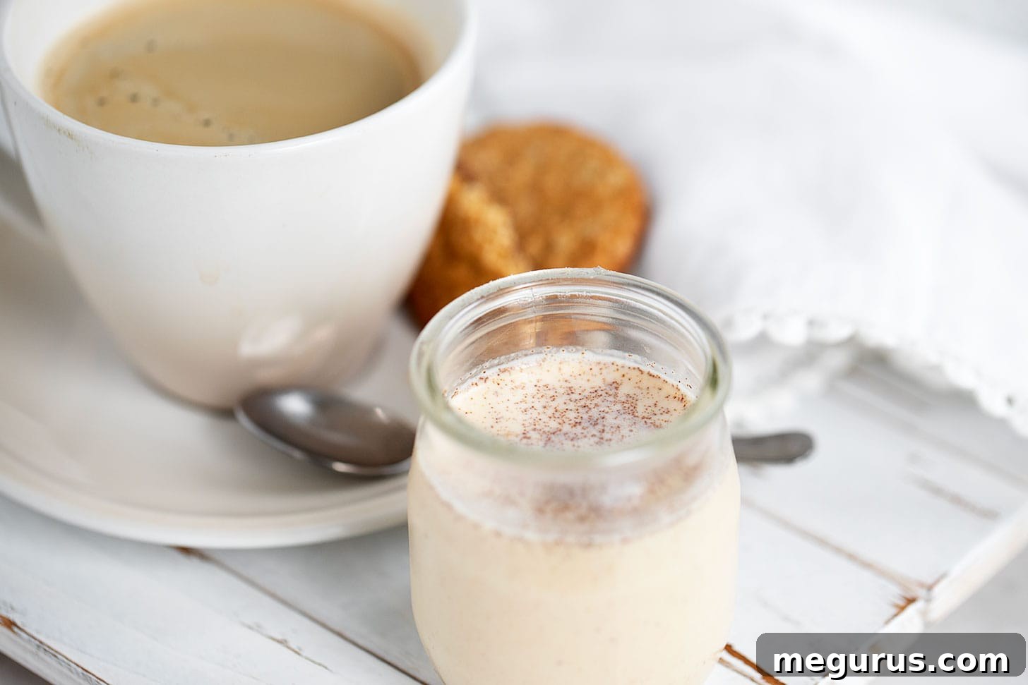A warm mug of pumpkin spice coffee with a bottle of homemade pumpkin spice coffee creamer in the foreground, perfect for fall mornings.