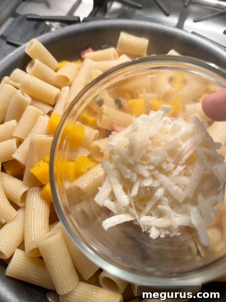 Grated Pecorino cheese being stirred into the pasta sauce, melting into creaminess.