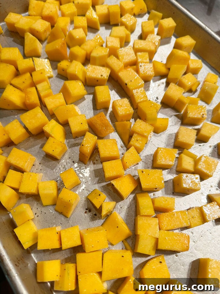 Butternut squash cubes spread on a baking sheet, ready for roasting.