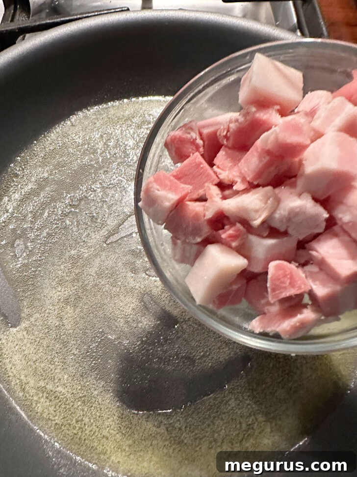 Diced pancetta sizzling in a skillet with melted butter.