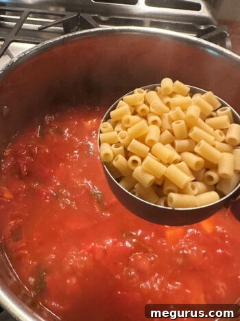 Adding small pasta to the pot.