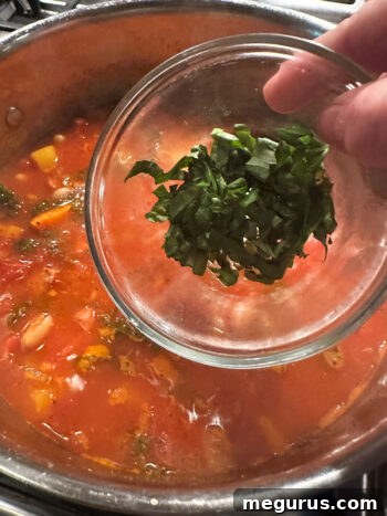 Adding fresh basil for a burst of aromatic flavor at the end.