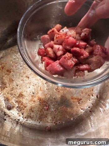 Removing cooked pancetta from the pot, leaving behind flavorful fat.