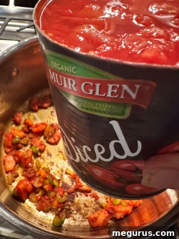 Pouring canned diced tomatoes into the pot.