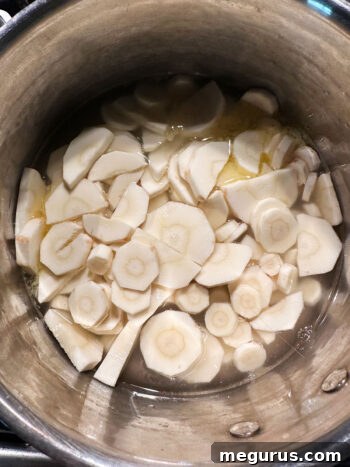 Peeled and sliced parsnips, butter, and broth added to a saucepan.