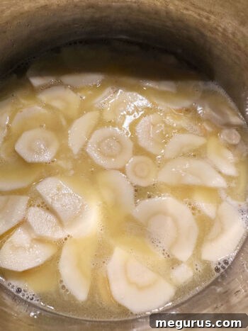 Parsnips and liquid coming to a boil in the saucepan.