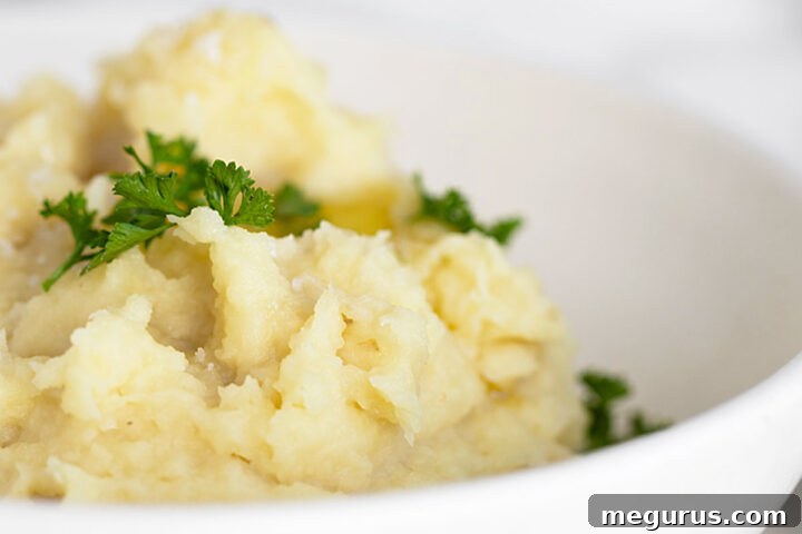 Parsnip puree in white bowl with parsley garnish.