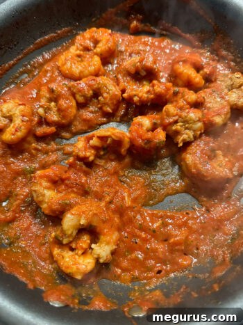 Returning the previously cooked shrimp back into the skillet with the sauce.