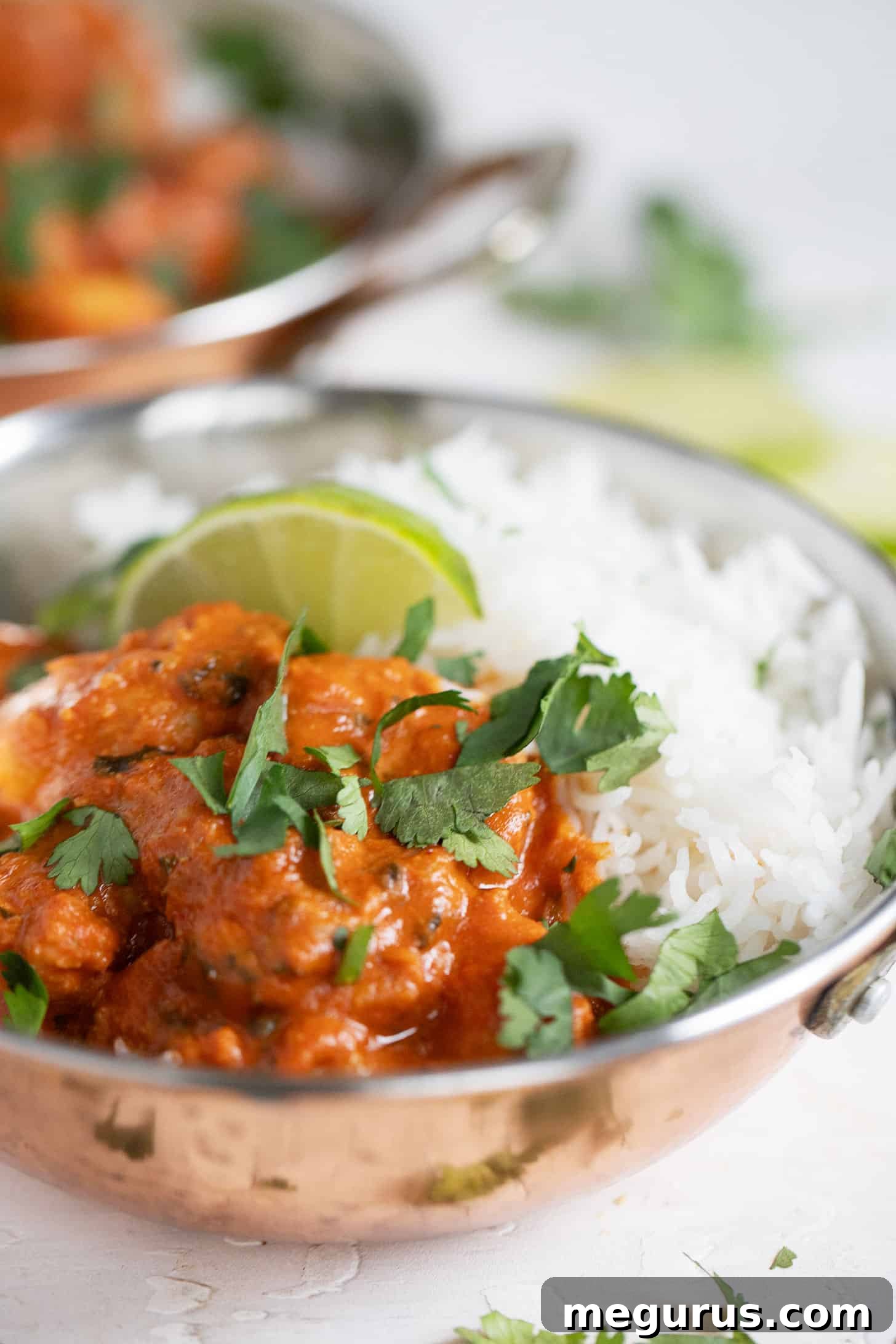 A close-up of a single copper bowl filled with Shrimp Tikka Masala and rice, highlighting the rich sauce and perfectly cooked shrimp.