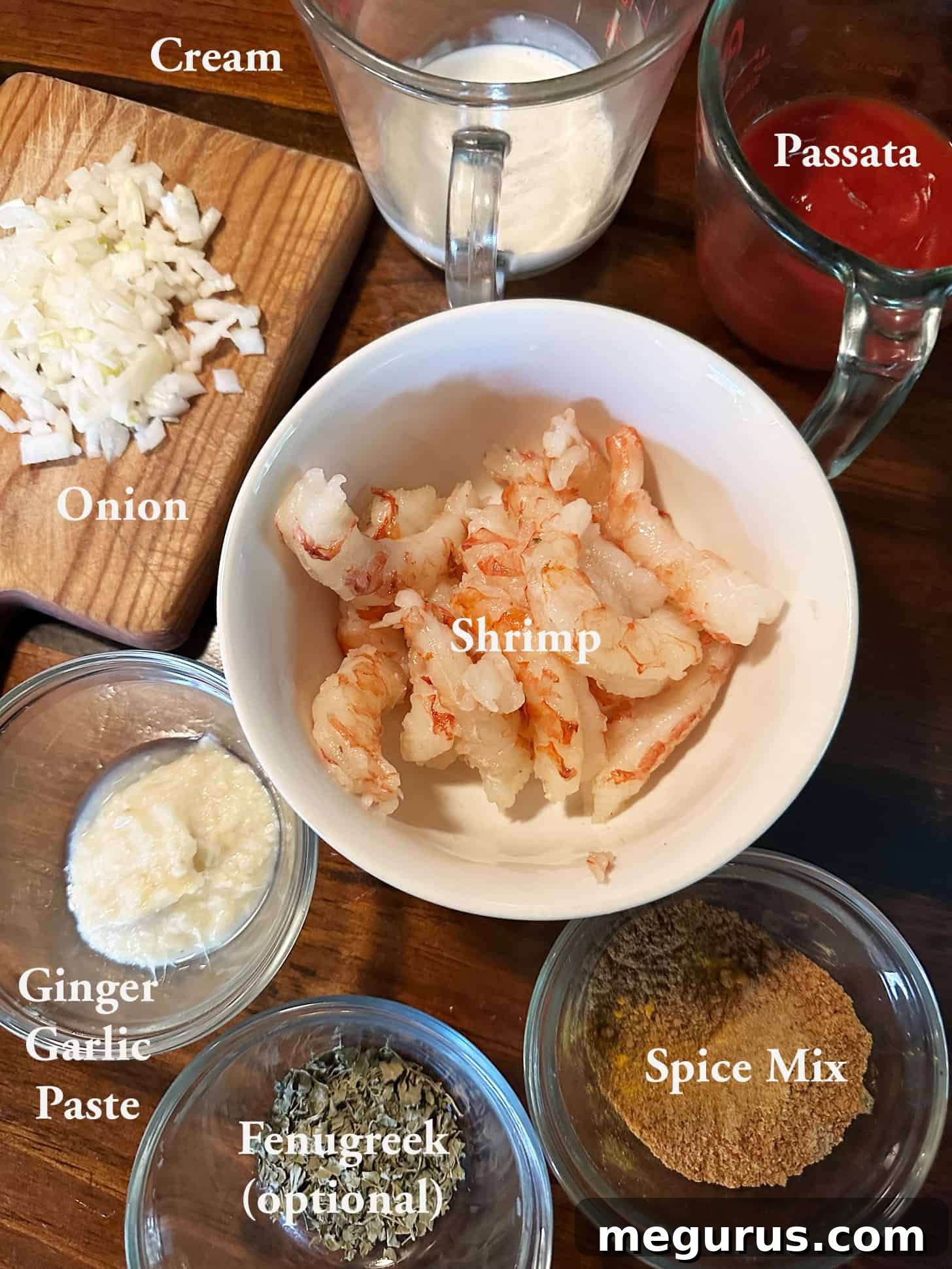 A selection of fresh ingredients laid out for making Shrimp Tikka Masala, including shrimp, tomatoes, spices, and cream.