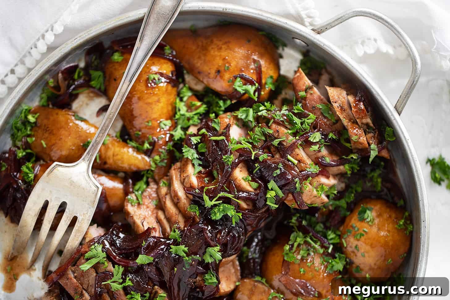 Pork tenderloin with pears and balsamic onions in serving dish, garnished with fresh parsley.