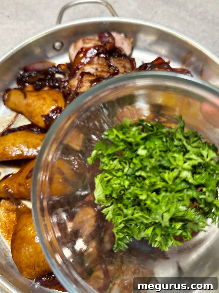 Beautifully plated pork tenderloin slices, sautéed pears, and balsamic onions, garnished with fresh parsley.