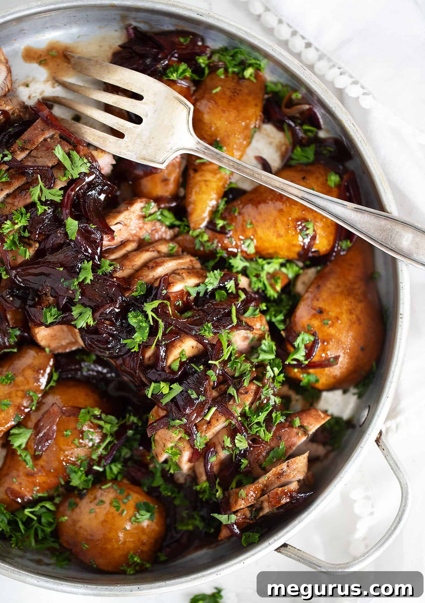 Pork tenderloin with pears and balsamic onions served in a dish with a fork, ready to eat.