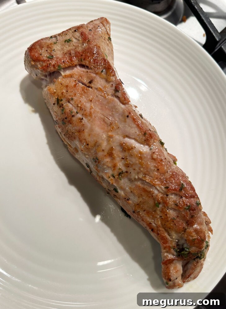 Pork tenderloin perfectly browned on all sides in a skillet.