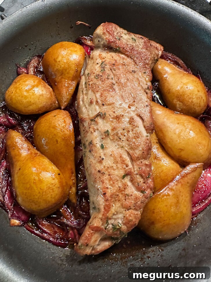 Pork tenderloin, pears, and onions after roasting in the oven, looking perfectly cooked.