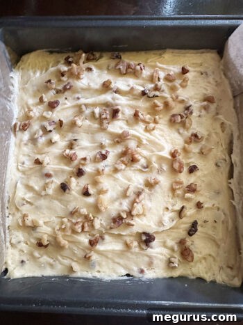 Blondie batter smoothed into a baking pan, topped with extra walnuts.