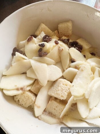 Pouring the warm milk mixture over the bread cubes and apples in a large bowl