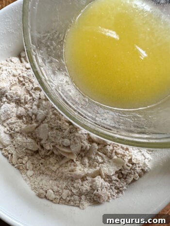 Melted butter being poured over the dry crumble topping ingredients.