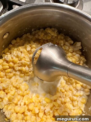 using an immersion blender to break down the corn for texture